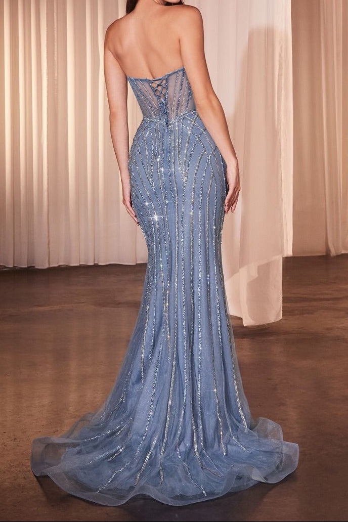 Woman wearing a blue evening gown with a lace-up back against a beige curtain background