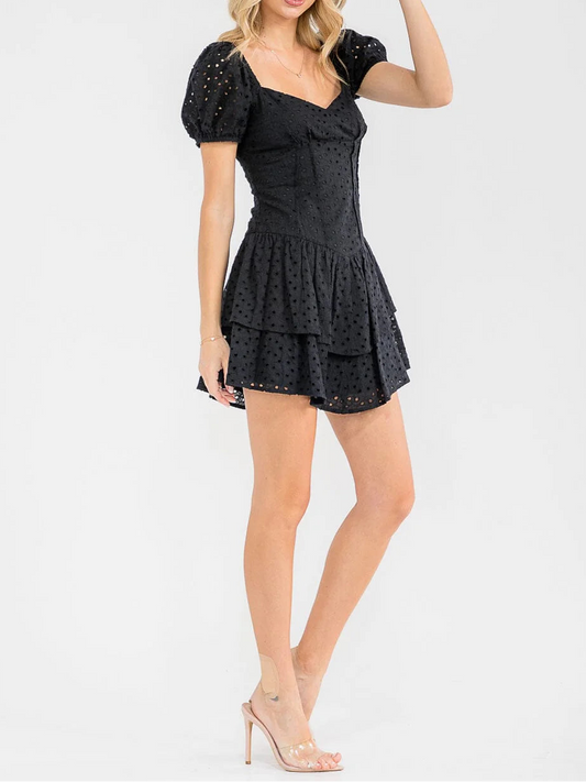 Woman wearing a black dress with puff sleeves and a hat on a white background