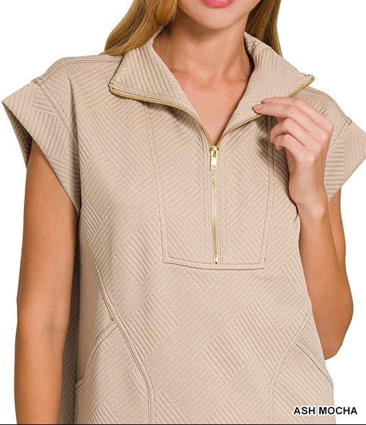 Woman wearing a beige sleeveless zip-up top on a white background