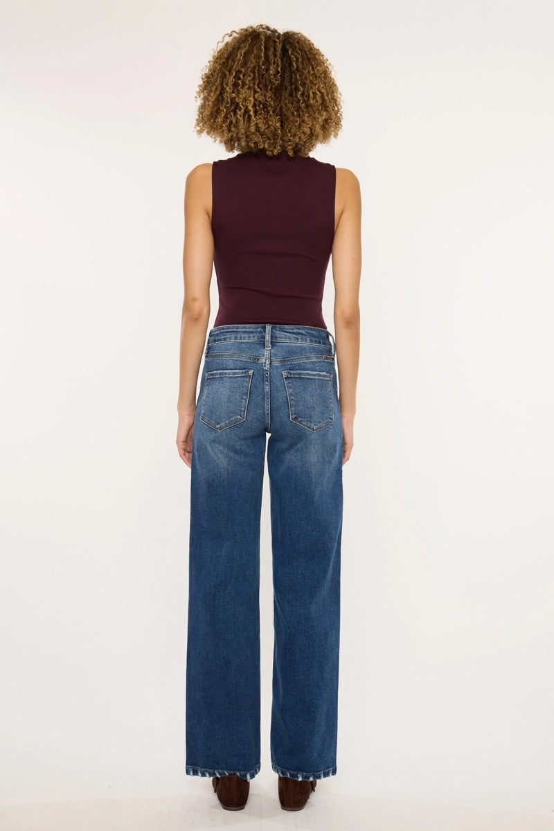 Person wearing blue jeans and a dark top on a white background