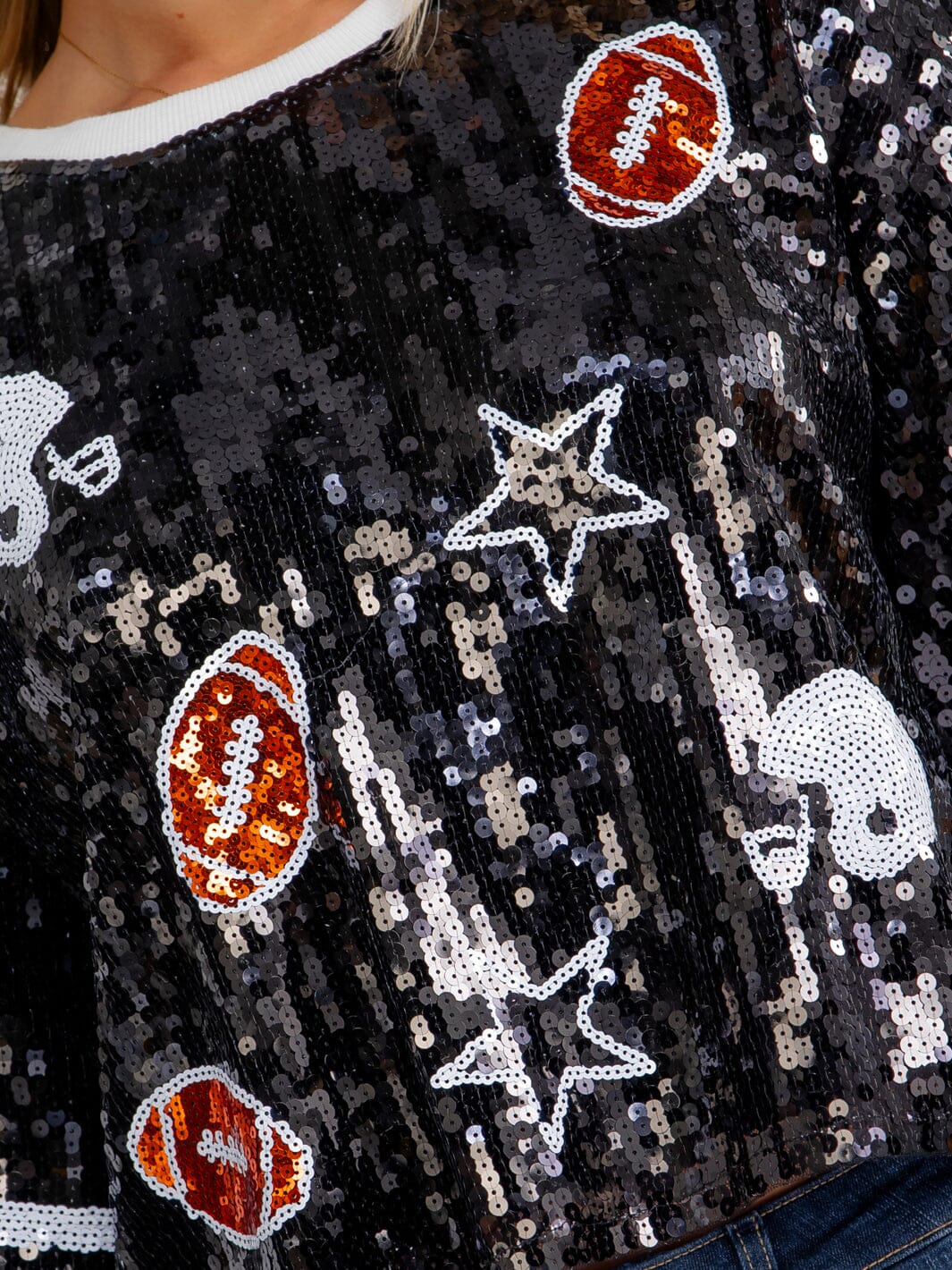 Black sequin sweater with football, star, and skeleton designs.